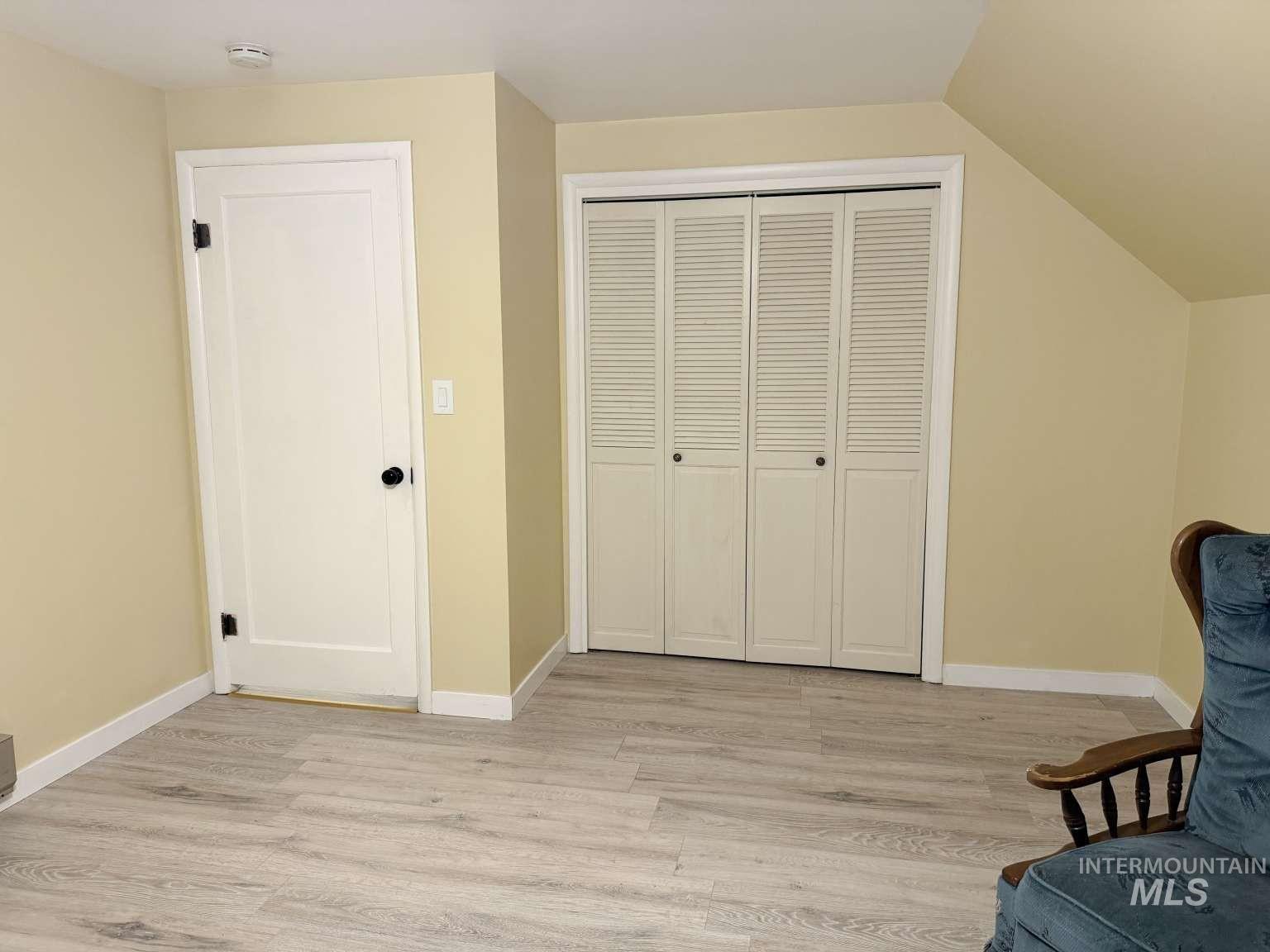 1158 South Powerline Road Nampa, ID 83686 - Photo 34 of 46 Room featuring light wood-finish flooring, a white paneled door with black hardware, and a louvered bifold closet