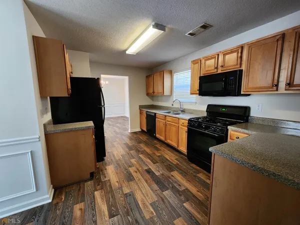 a kitchen with granite countertop a refrigerator stove top oven a sink and dishwasher