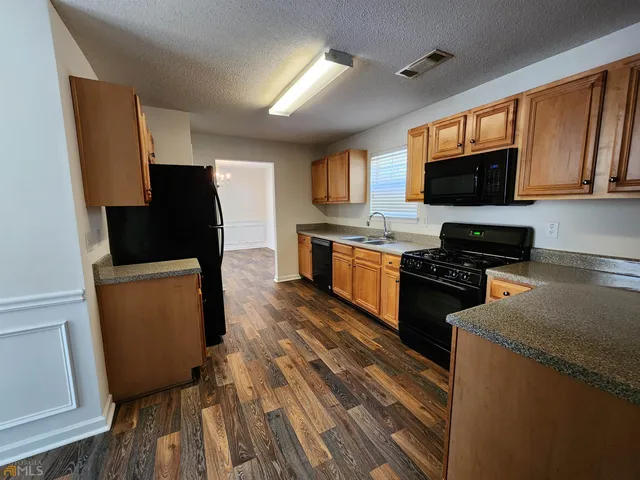 a kitchen with granite countertop a refrigerator stove top oven a sink and dishwasher
