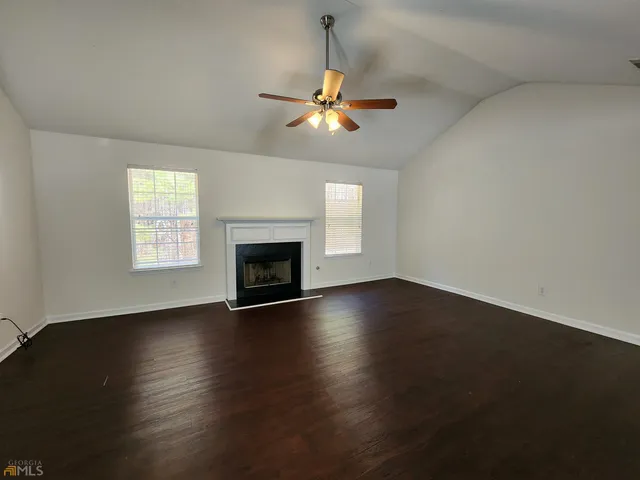 an empty room with wooden floor fireplace and a window