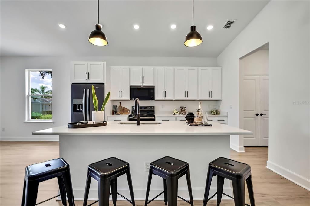 6589 Freeport Drive Spring Hill, FL 34608 - Photo 22 of 63 a kitchen with stainless steel appliances a white refrigerator a sink dishwasher a dining table and chairs with wooden floor