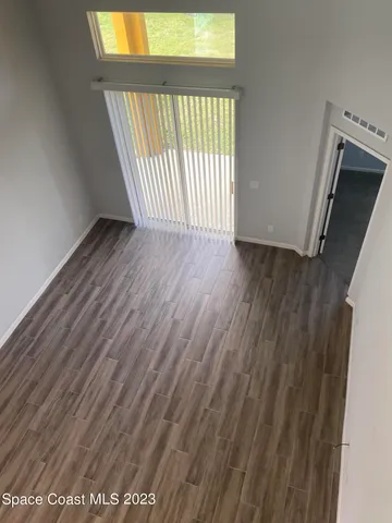 a view of an empty room with wooden floor and a window