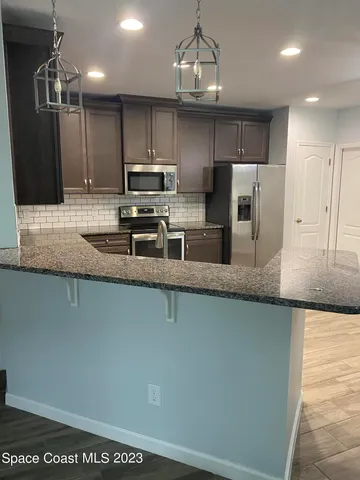 a kitchen with stainless steel appliances granite countertop a sink a stove top oven a counter space and cabinets