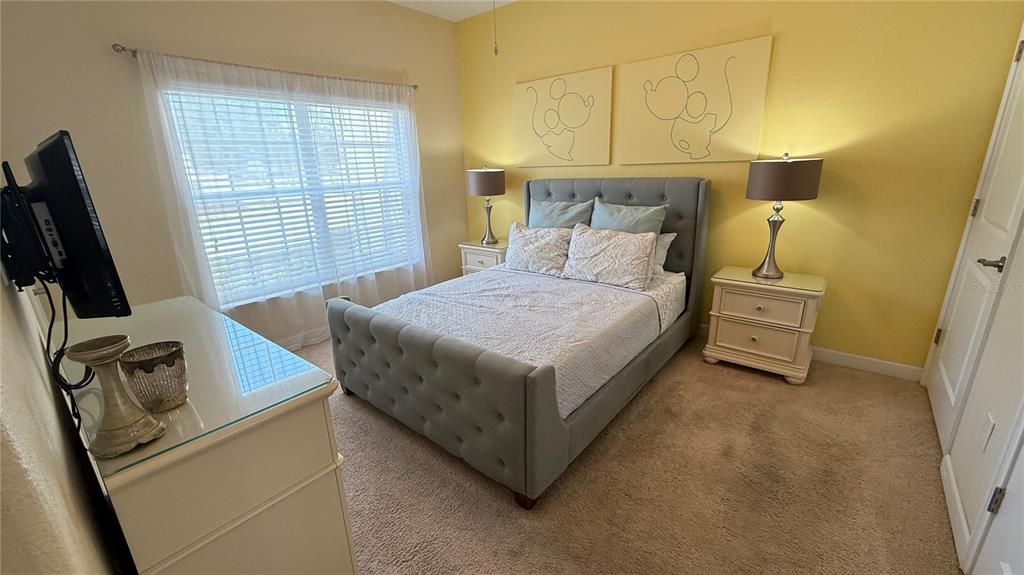 4794 Clock Tower Drive Kissimmee, FL 34746 - Photo 15 of 63 a bedroom with a bed a couch and a flat tv screen on the dresser