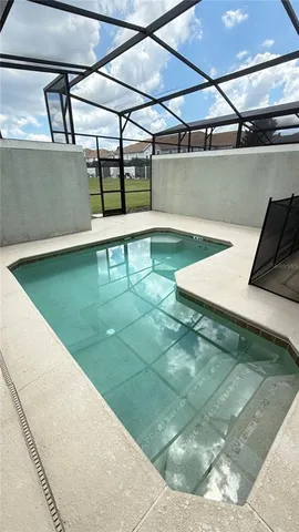 a view of a swimming pool with lawn chairs and a big yard