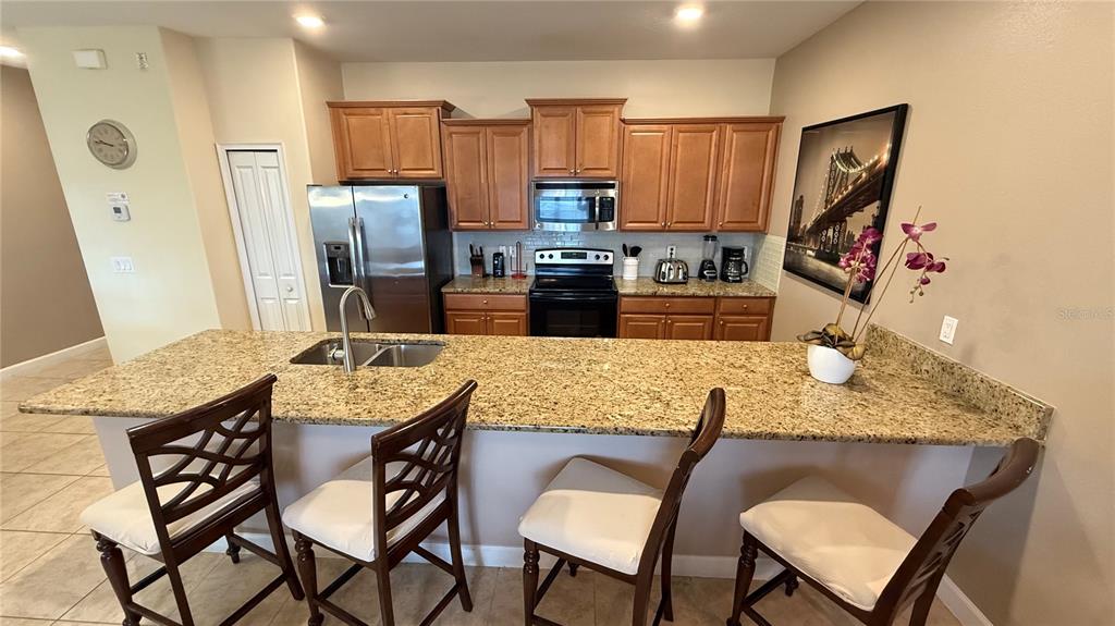 4794 Clock Tower Drive Kissimmee, FL 34746 - Photo 5 of 63 a kitchen with stainless steel appliances granite countertop a table chairs and a refrigerator