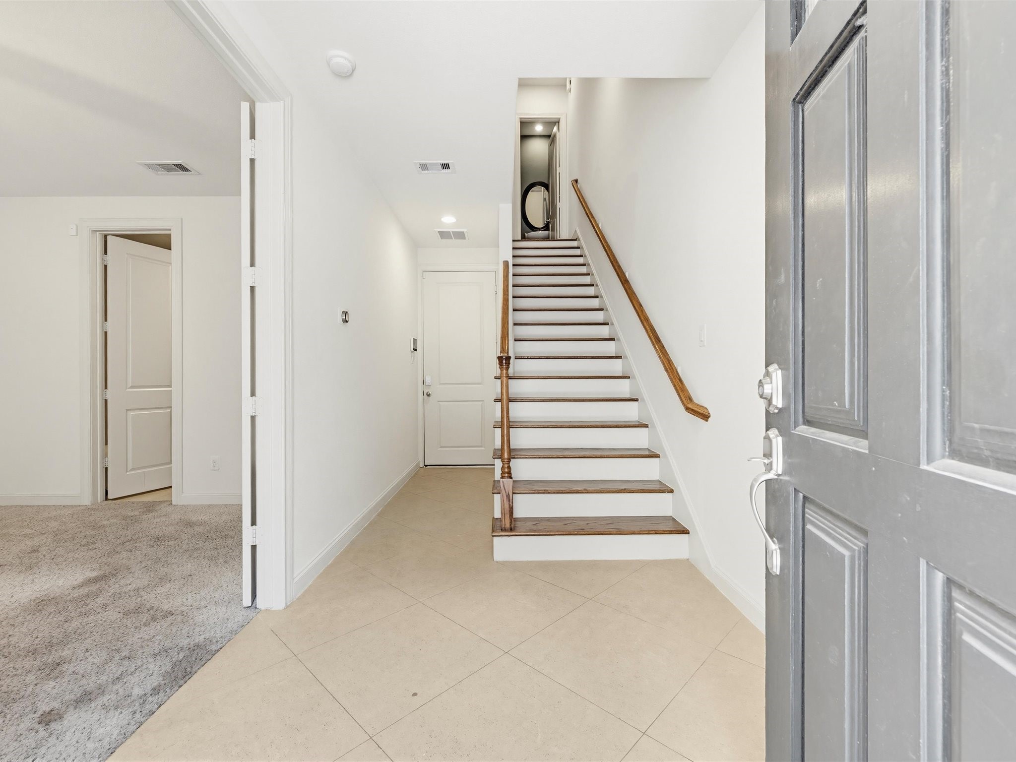 9427 London Bridge Station Houston, TX 77045 - Photo 4 of 30 Step into this bright and welcoming entryway featuring a white front door with sidelights, elegant neutral tile flooring, and a stylish staircase with a wooden handrail and iron balusters.