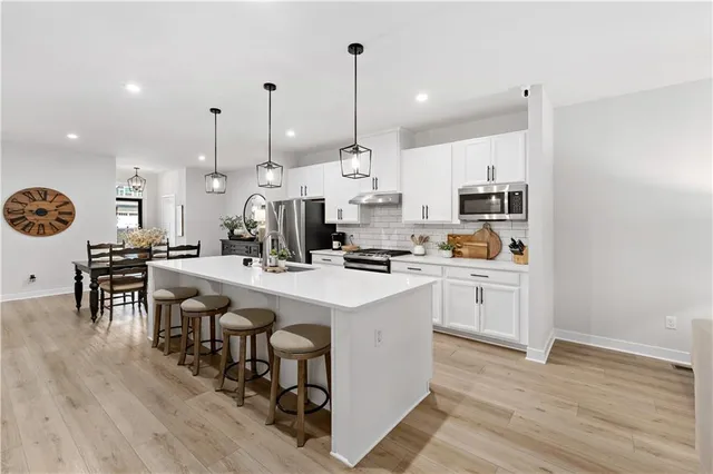 a kitchen with stainless steel appliances kitchen island granite countertop a sink a stove and a wooden floors