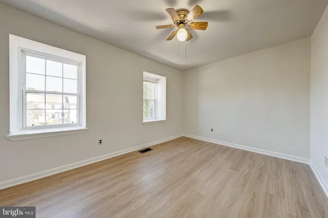 a view of an empty room with a window and wooden floor