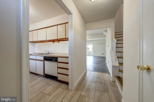 a view of a hallway with wooden floor and a kitchen