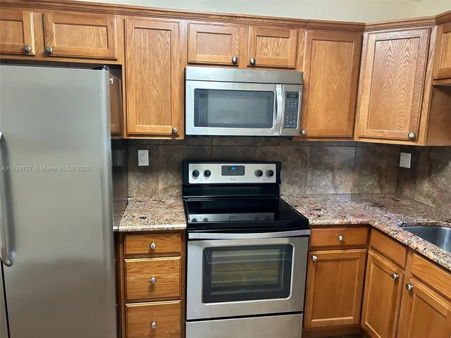 a kitchen with stainless steel appliances granite countertop a refrigerator and a stove