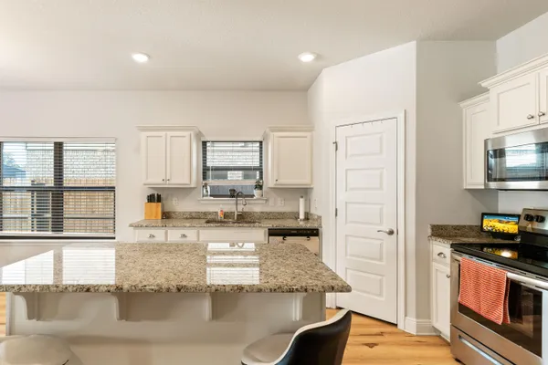 a kitchen with granite countertop a stove a sink and a refrigerator