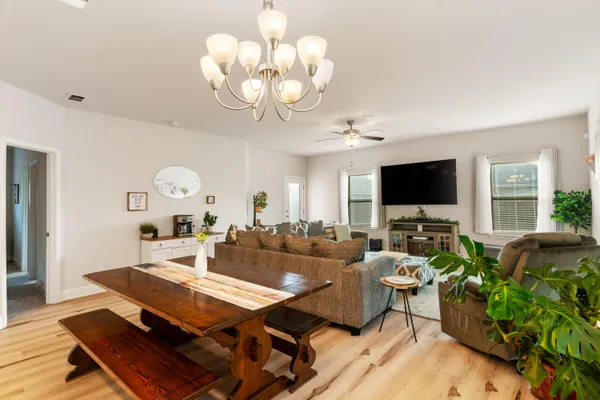 a kitchen with stainless steel appliances kitchen island granite countertop a refrigerator a stove a sink dishwasher and a dining table with wooden floor