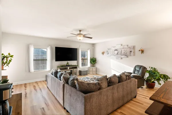 a living room with furniture kitchen view and a chandelier