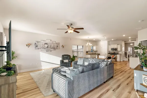 a living room with furniture kitchen view and a chandelier