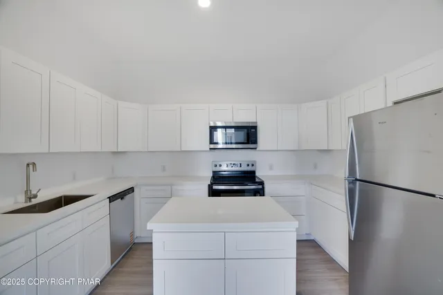 a kitchen with a sink a refrigerator and white cabinets