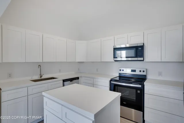 a kitchen with stainless steel appliances a sink a stove a microwave and cabinets