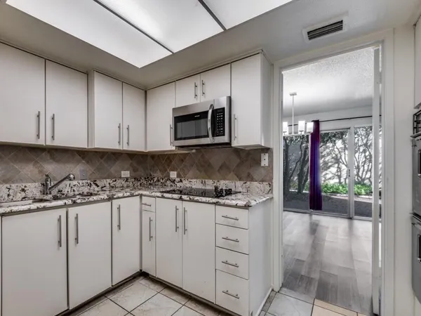a kitchen with granite countertop white cabinets and stainless steel appliances