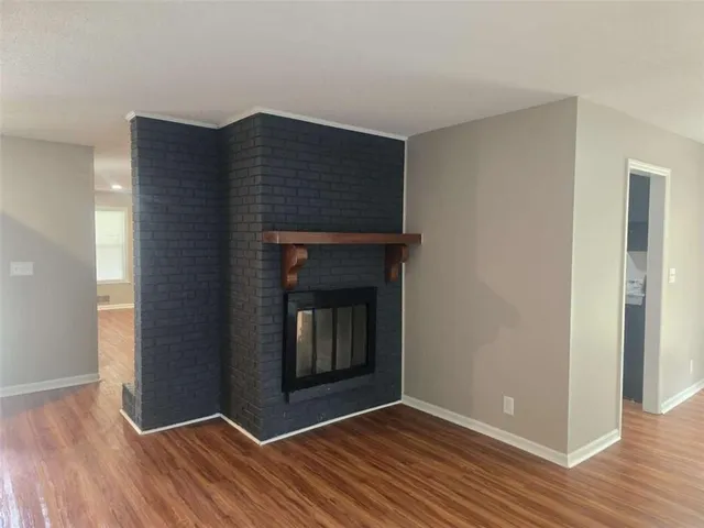 a view of an empty room with wooden floor and a fireplace