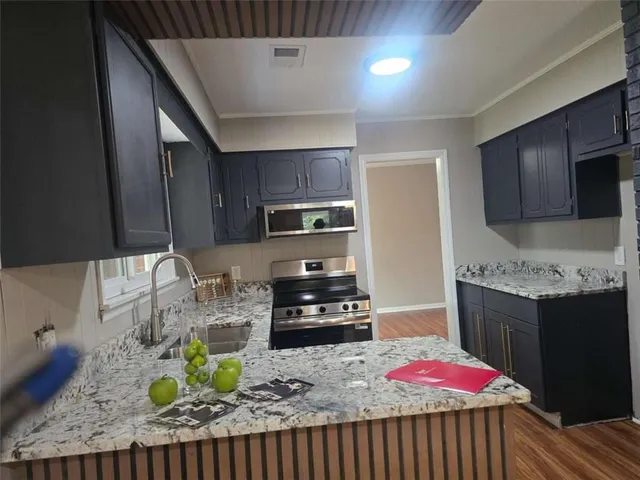 a kitchen with stainless steel appliances granite countertop a stove refrigerator and a microwave