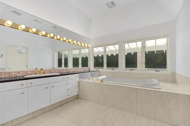 a spacious bathroom with a granite countertop tub and a large window