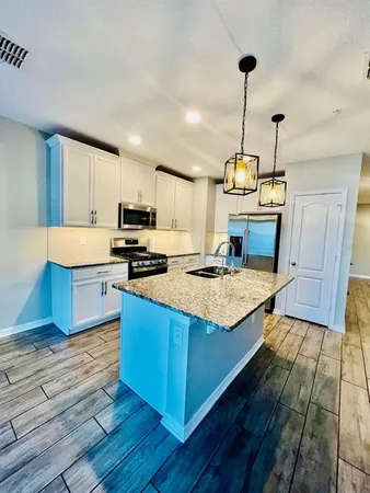 a kitchen with kitchen island granite countertop wooden floors and stainless steel appliances