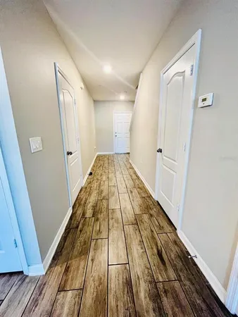 a view of wooden floor in a hallway with a window