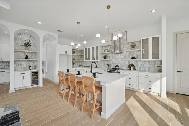 a large white kitchen with lots of counter space wooden floor and appliances