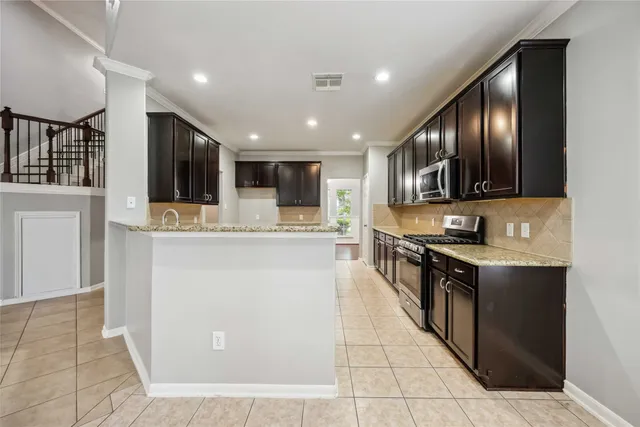 a large kitchen with stainless steel appliances kitchen island granite countertop a refrigerator and a stove top oven