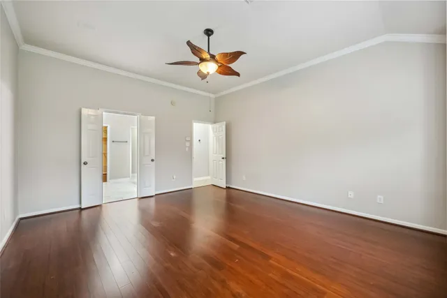 an empty room with wooden floor a ceiling fan and windows