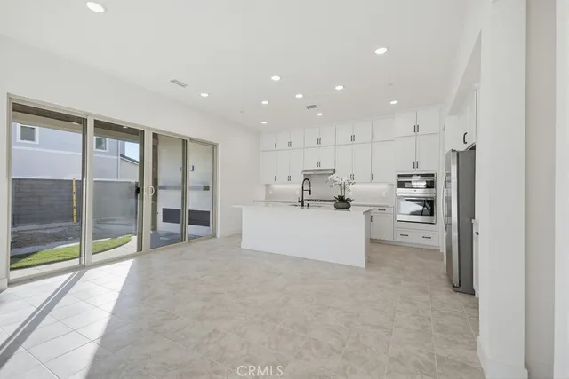 a kitchen with white cabinets a sink a stove and a refrigerator