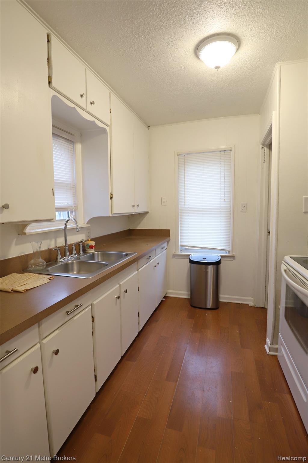 2074 North Center Road Burton, MI 48509 - Photo 10 of 20 Kitchen featuring white cabinetry, a textured ceiling, dark wood-style flooring, white electric range oven, and light countertops