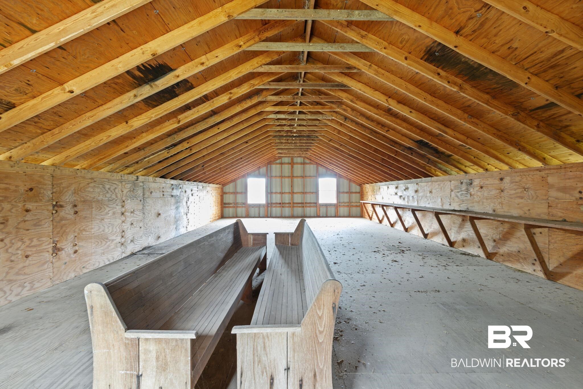 7540 2 Mile Road Irvington, AL 36544 - Photo 60 of 82 Spacious attic space featuring exposed wood rafters, plywood walls, and gabled windows