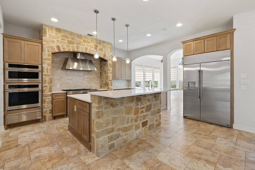 109 Largo Cove Austin, TX 78734 - Photo 10 of 40 A chef's kitchen features stainless steel appliances, stone accents, and a large central island for gathering.