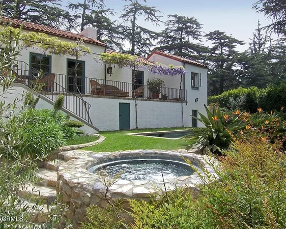 a view of a house with a small yard and large tree