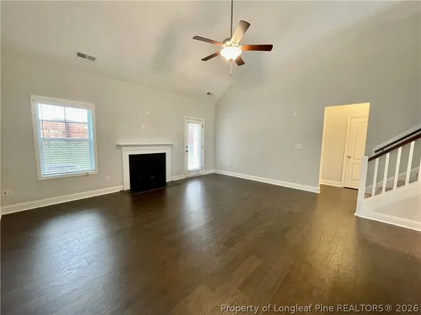 an empty room with wooden floor fireplace and windows