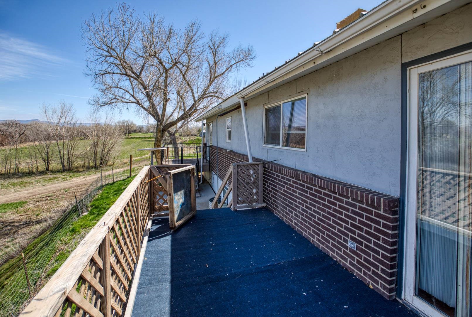 1179 17 Road Fruita, CO 81521 - Photo 18 of 36 a balcony with wooden floor and fence next to a yard