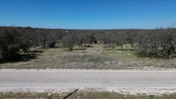 a view of a dry field with trees in background