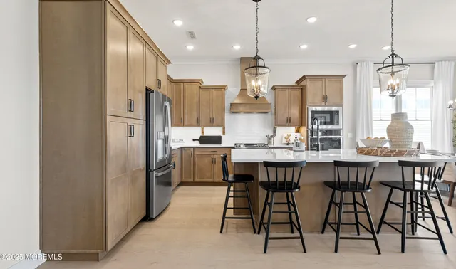 a kitchen with stainless steel appliances a dining table chairs refrigerator and microwave
