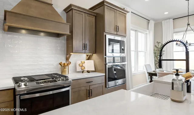 a kitchen with stainless steel appliances kitchen island granite countertop a dining table chairs refrigerator and microwave