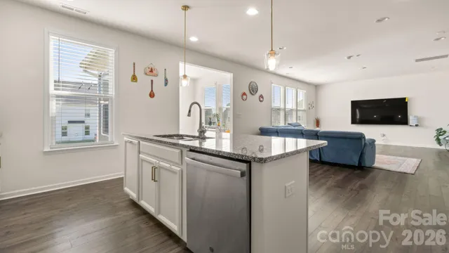 a kitchen with stainless steel appliances granite countertop a sink a stove and a wooden floors