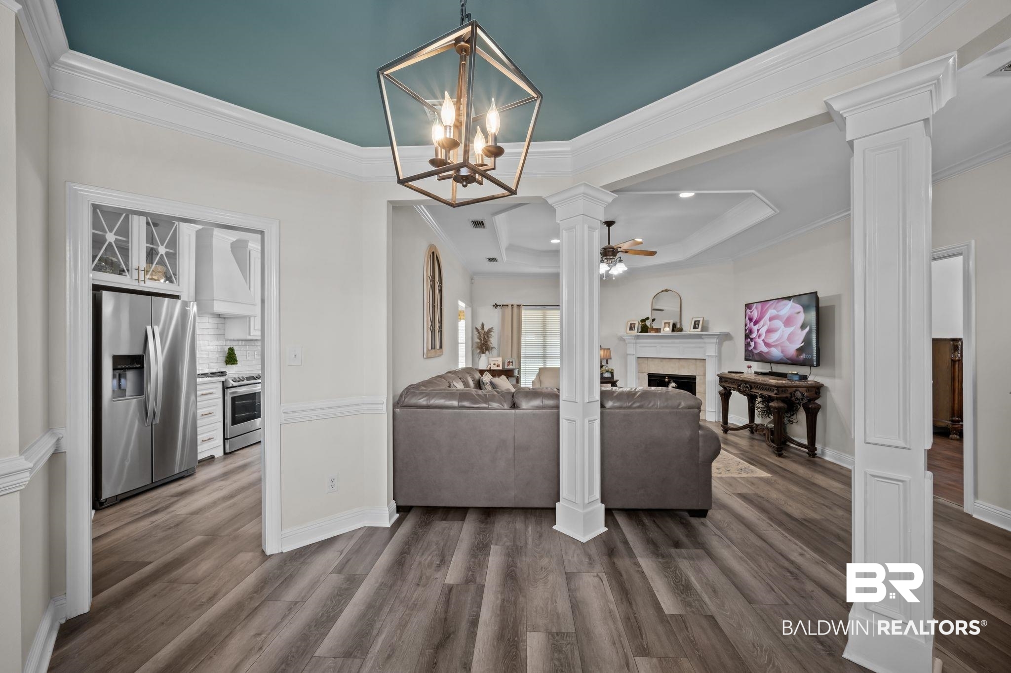 9837 Harmony Ridge Drive Semmes, AL 36575 - Photo 7 of 29 Living room with crown molding, ornate columns, ceiling fan with notable chandelier, dark wood finished floors, and a fireplace