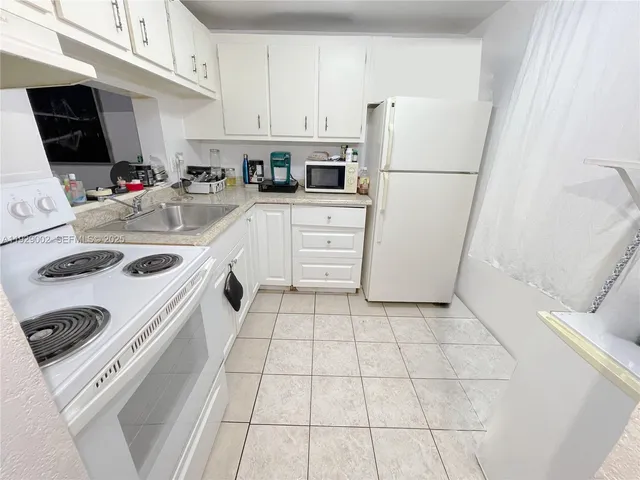 a kitchen with white cabinets and white appliances