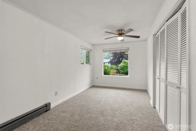 an empty room with windows and a ceiling fan
