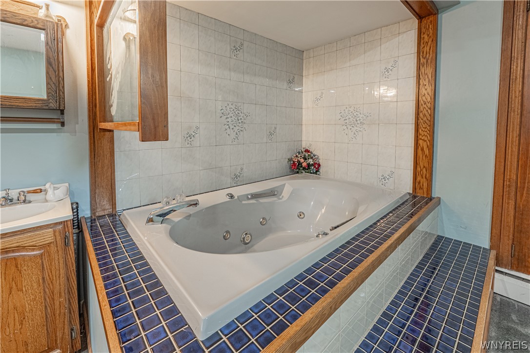 6775 Bear Ridge Road Pendleton, NY 14094 - Photo 20 of 48 Tiled surround frames a large soaking tub, creating a dedicated space for relaxation.
