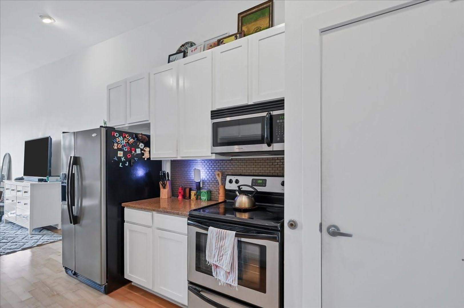 2931 East 12th Street, Unit 306 Austin, TX 78702 - Photo 5 of 19 a kitchen with stainless steel appliances granite countertop a refrigerator stove and microwave