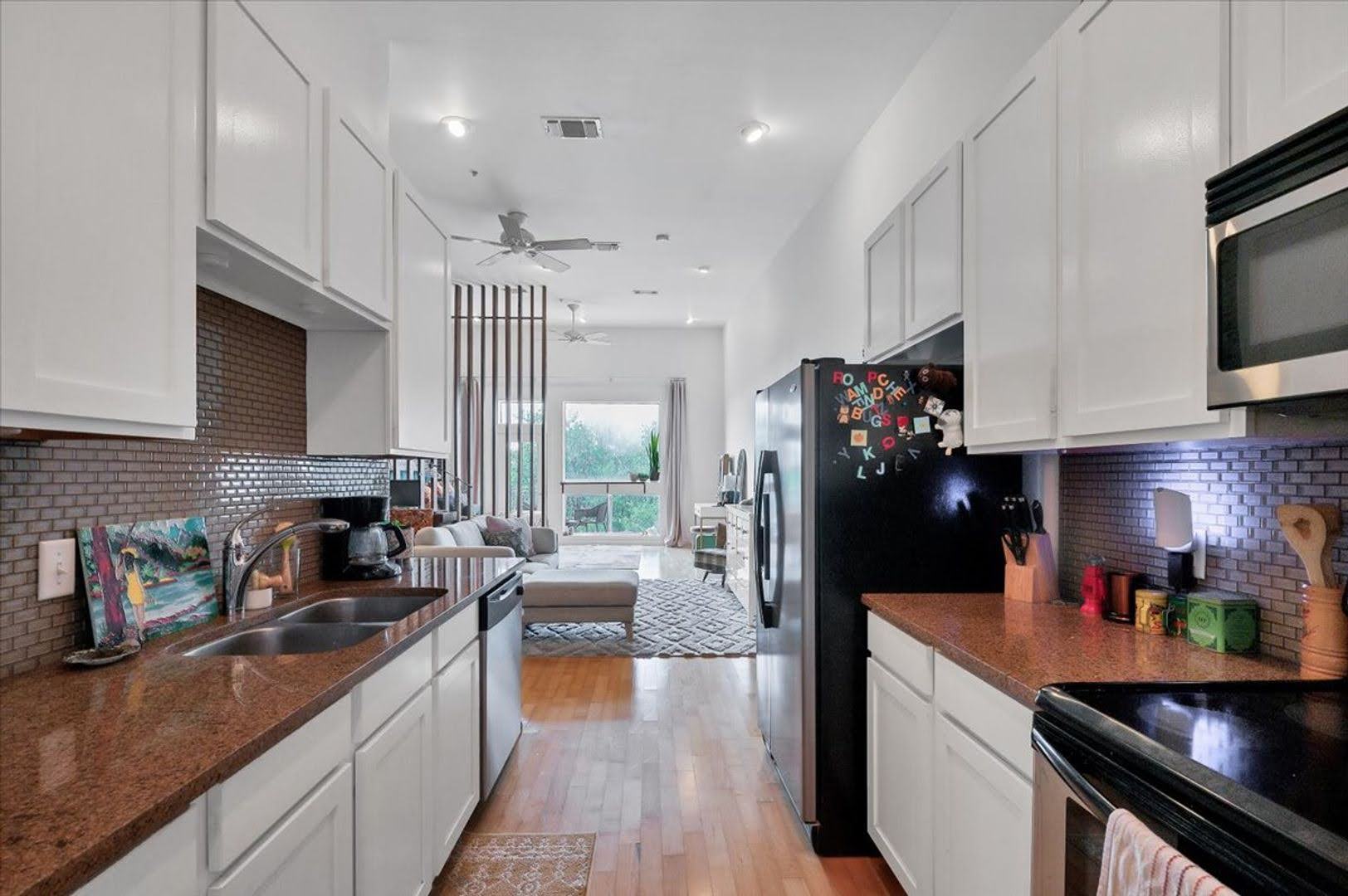 2931 East 12th Street, Unit 306 Austin, TX 78702 - Photo 6 of 19 a kitchen with stainless steel appliances granite countertop a refrigerator a sink dishwasher a stove and white countertops with wooden floor
