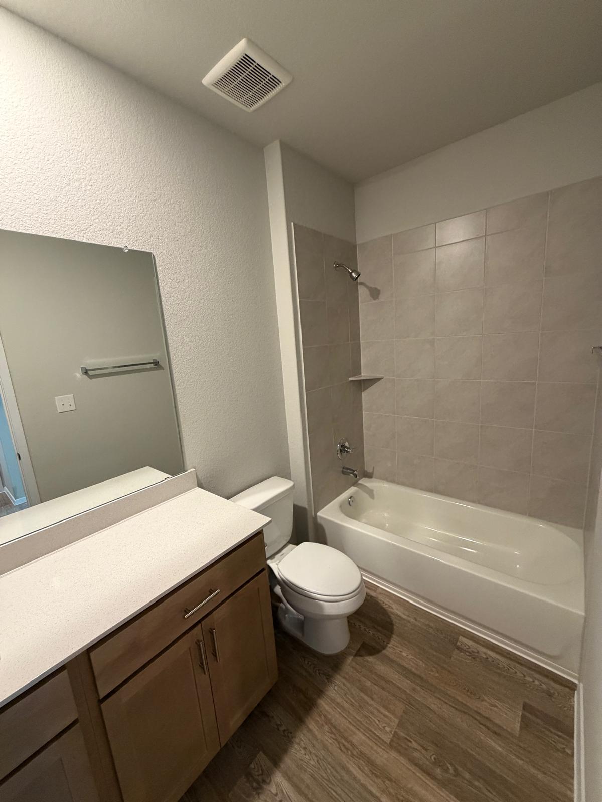 2701 Towy Road Manor, TX 78653 - Photo 17 of 35 A well-appointed bathroom featuring a clean vanity with a large mirror and a tiled tub-shower combination.