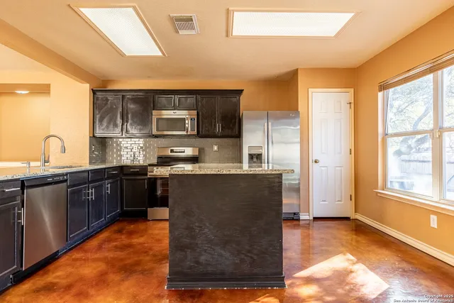 a kitchen with granite countertop a refrigerator and a stove top oven