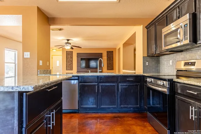 a kitchen with stainless steel appliances granite countertop a stove a sink and a microwave